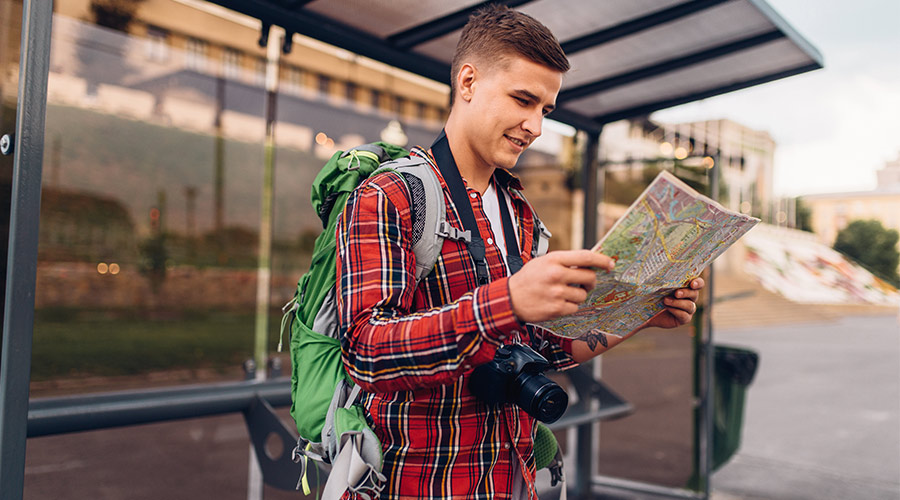 man standing at bus stop with map