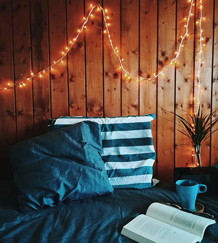 dorm room with fairy lights coffee mug and book