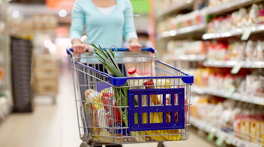 woman pushing full trolley at grocery store