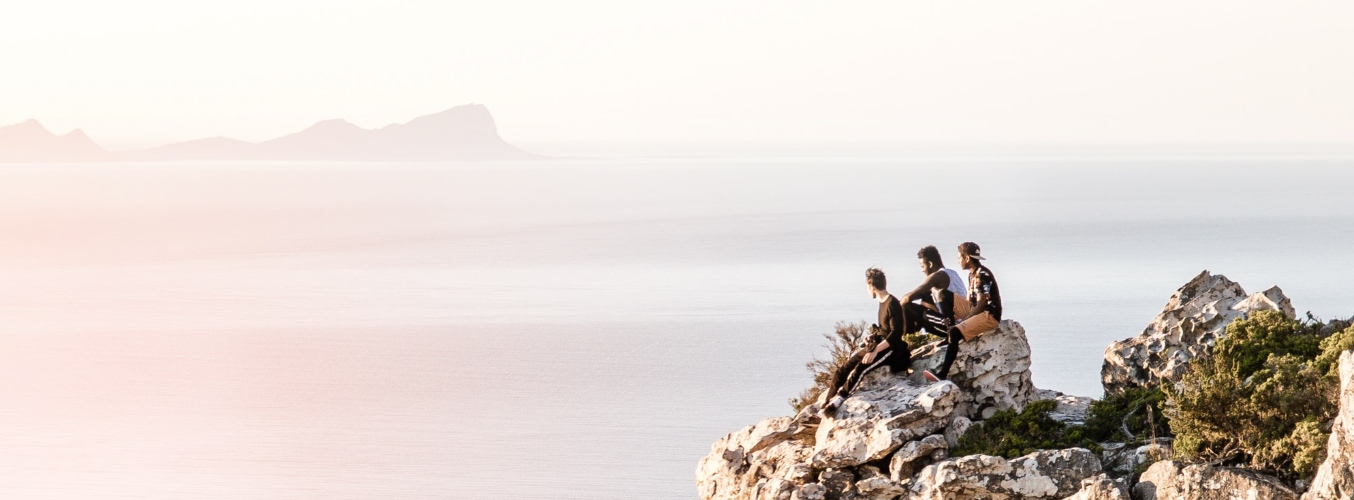 Friends watching the sunset on a mountain in Muizenberg